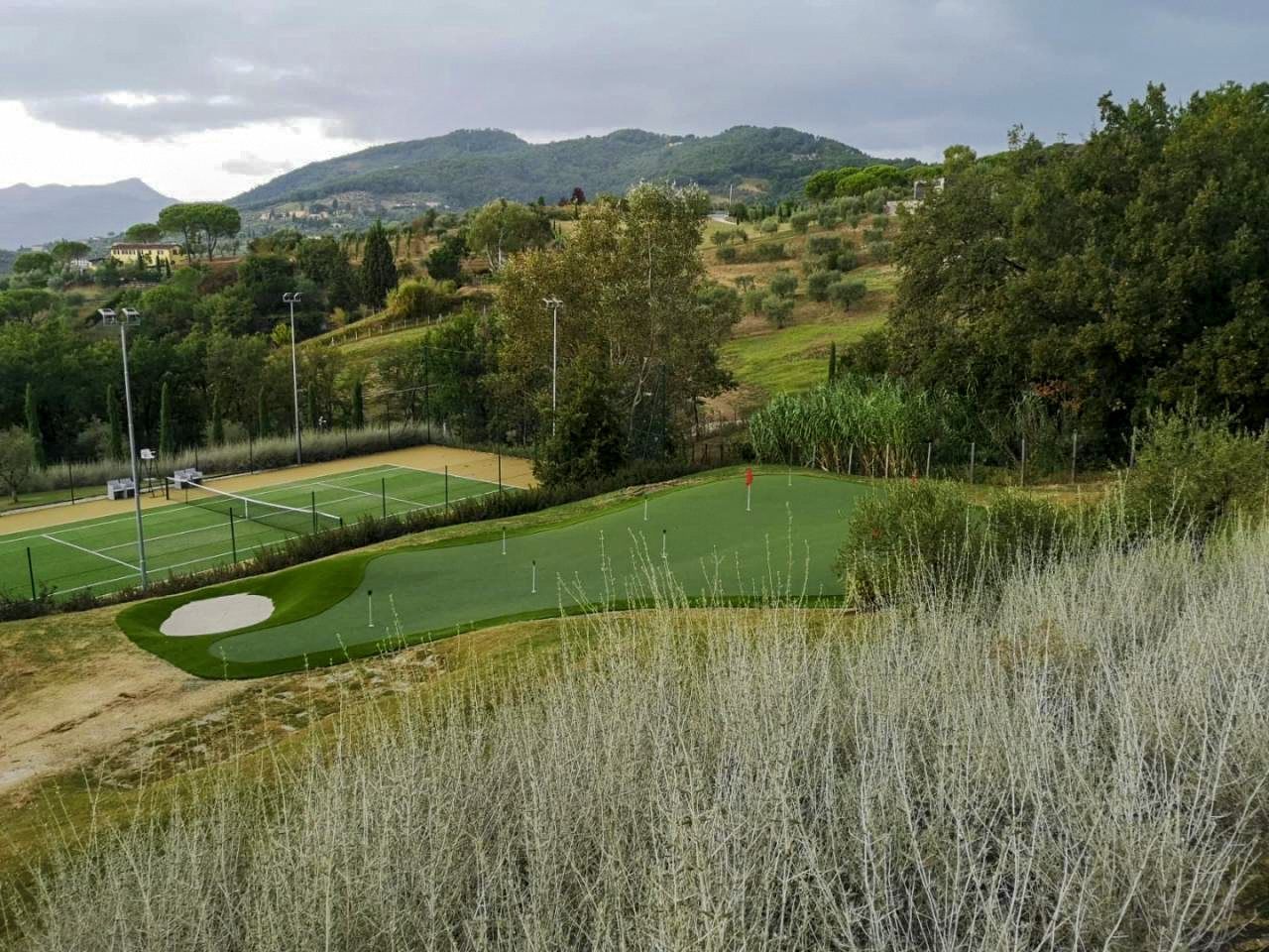 Putting green with bunker beside a tennis court